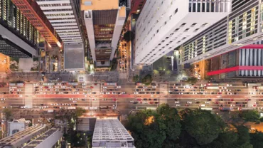 Aerial view of a busy urban street with cars and tall buildings.