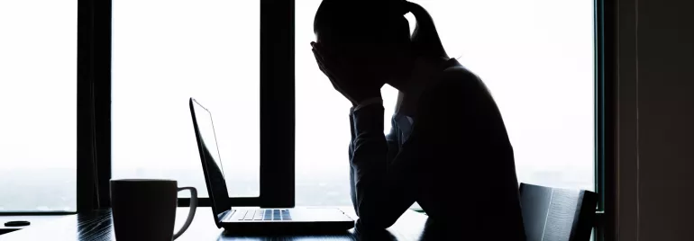 Uma mulher em frente a um computador com as mãos na cabeça mostrando descontentamento 
